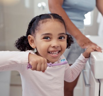 Smiling child brushing teeth in bathroom