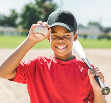 Closeup of child holding baseball and baseball bat